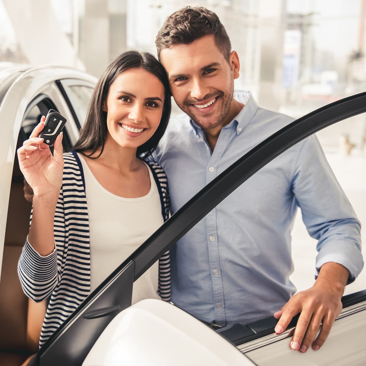 Couple holding a key for their new novated lease vehicle, looking at camera and smiling. Couple holding a key for their new novated lease vehicle, looking at camera and smiling.