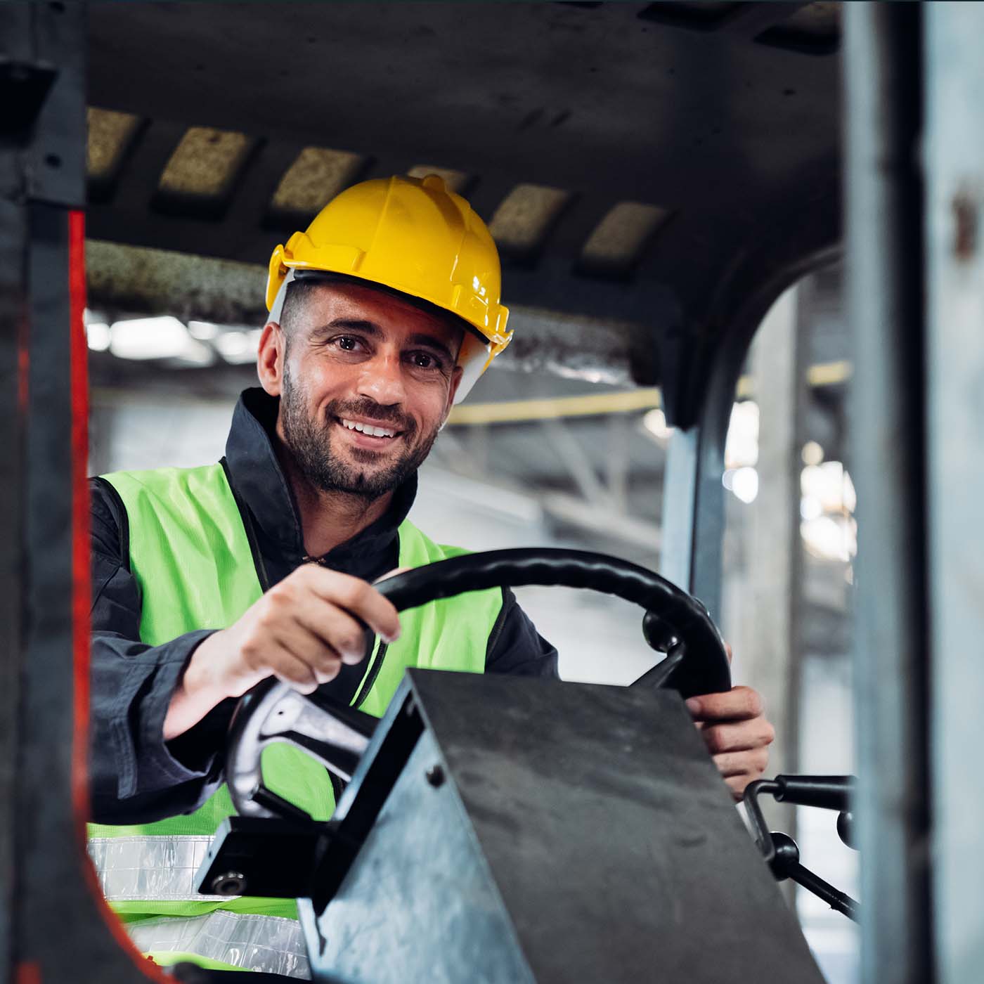 A worker drives a forklift wearing a safety helmet and reflective vest in the warehouse. A worker drives a forklift wearing a safety helmet and reflective vest in the warehouse.
