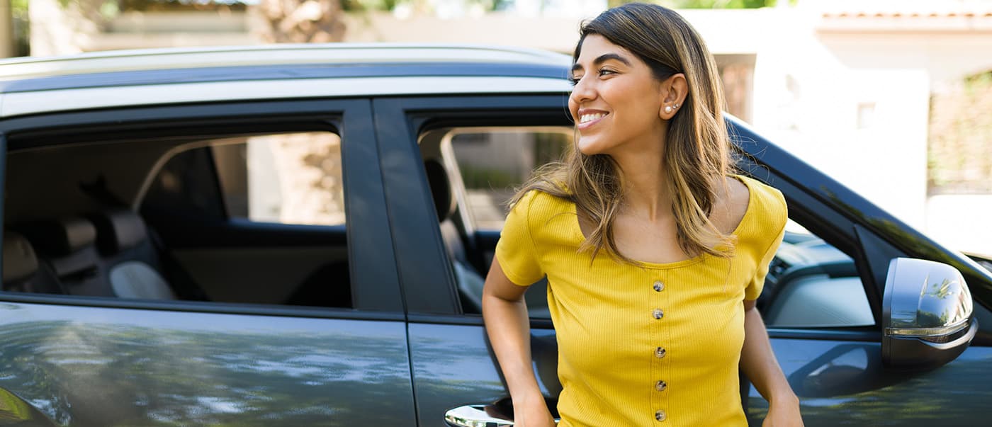 Happy woman leaning on her new car and laughing during a beautiful day outside. Happy woman leaning on her new car and laughing during a beautiful day outside.